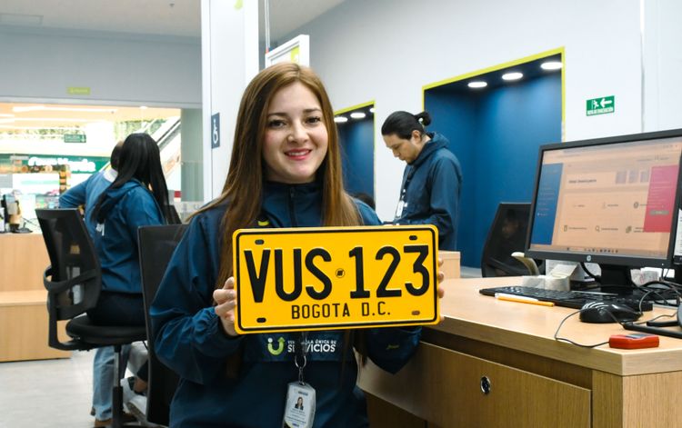 Analista de la Ventanilla Única de Servicios sostiene una placa de carro matriculada en Bogotá. - Foto: Valentina Bachiller © Consorcio Circulemos Digital, 2026