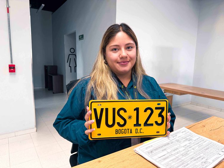 Analista de la Ventanilla Única de Servicios sostiene la placa de un vehículo matriculado en Bogotá - Foto: Valentina Bachiller © Consorcio Circulemos Digital, 2026