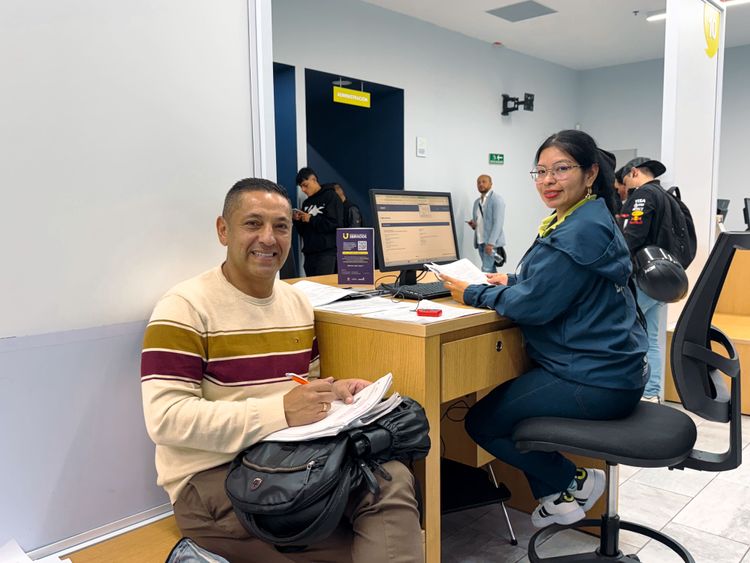 Ciudadano y analista sonríen mientras realizan un trámite de tránsito y transporte en la Ventanilla Única de Servicios - Foto: Valentina Bachiller © Consorcio Circulemos Digital, 2026